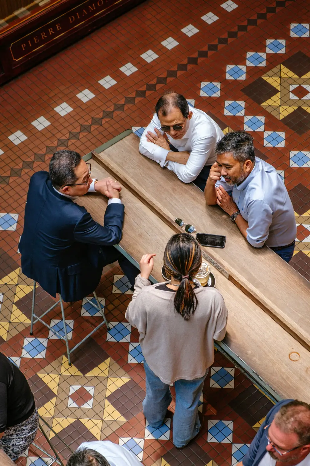 Profesionales conversan alrededor de una mesa de trabajo sobre piso de mosaico tradicional